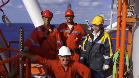 Engineers in boiler suites on a vessel at sea.